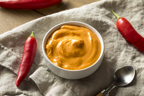 spicy Sriracha aioli in a bowl with red chili peppers