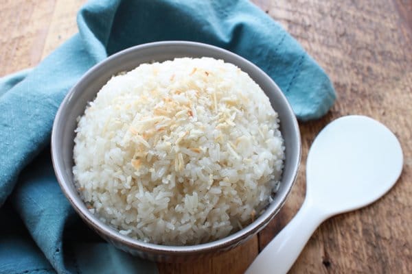 white rice in a gray bowl with a white spoon and blue napkin on the side