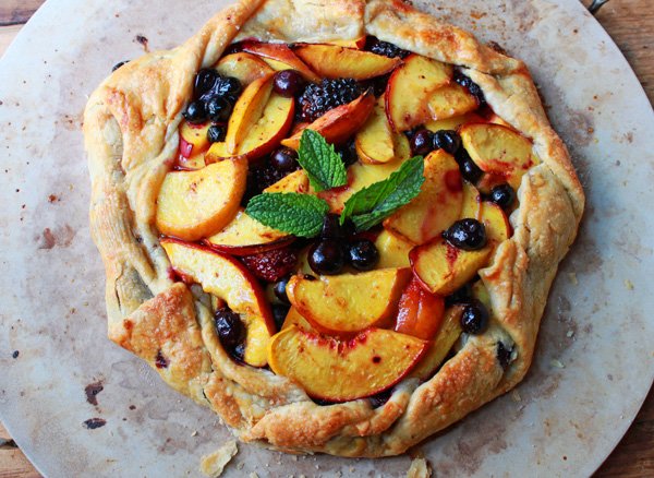 a rustic summer fruit tart ontop of a ceramic surface