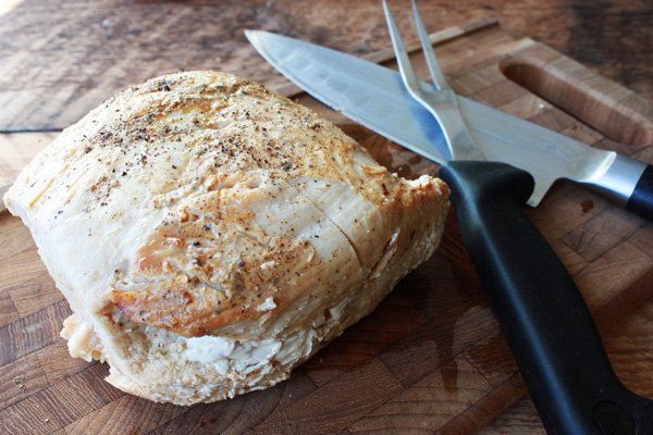 Thanksgiving turkey breast a cooked turkey breast on top of a wooden cutting board with a chef's knife and fork along side