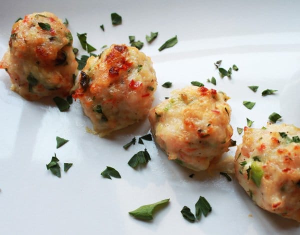 Baked shrimp meatballs in a row on top of a white platter.