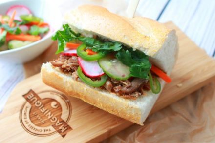 A pulled pork banh mi sandwich on a wooden board