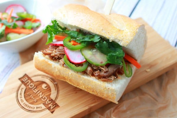 A pulled pork banh mi sandwich on a wooden board