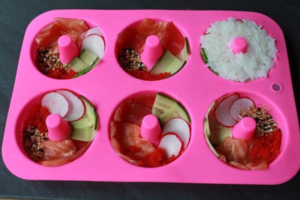 sushi donuts ingredients layered in a pink silicone donut mold