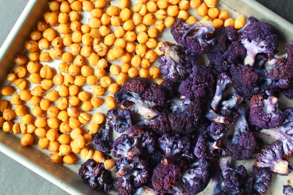 Roasted purple cauliflower florets and chickpeas on a sheet pan.