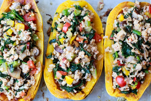 delicata squash stuffed with veggies and rice on a baking tray ready to be put in the oven