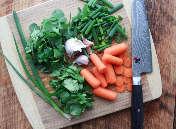 mixed raw veggies mixed raw veggies on top of a wooden cutting board with a chefs knife along side