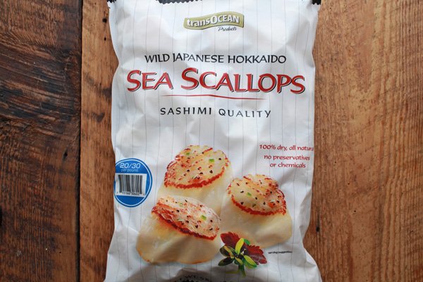 sea scallops A large bag of frozen wild sea scallops from TransOcean sitting on top of a wooden board.