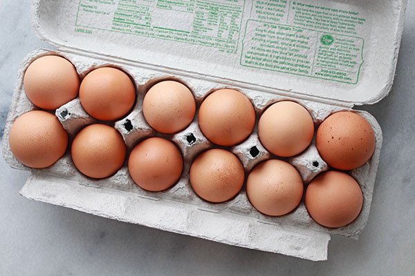 a dozen brown eggs in an egg crate