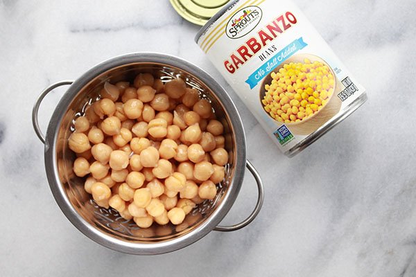 garbanzo beans hummus chickpeas chickpeas garbanzo beans in a silver strainer with a can of garbanzo beans on the side on top of a marble surface