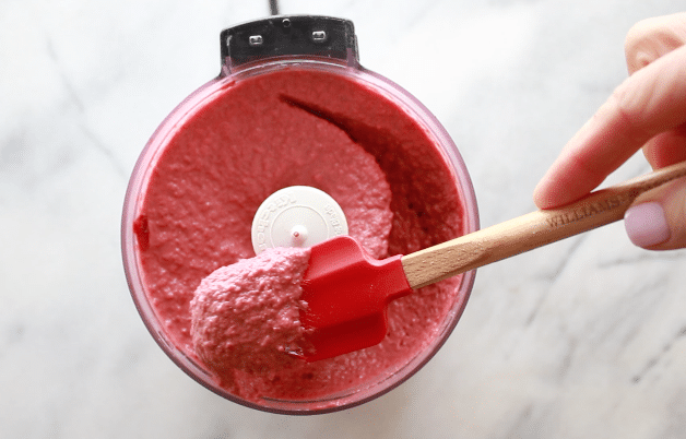 Red Beet Hummus red beet hummus pureed in a small food processor with a red rubber spatula