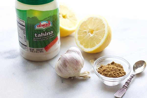 tahini tahina lemons garlic cumin tahini tahina in a jar with lemons, garlic, and a bowl of cumin on the side with a small silver spoon