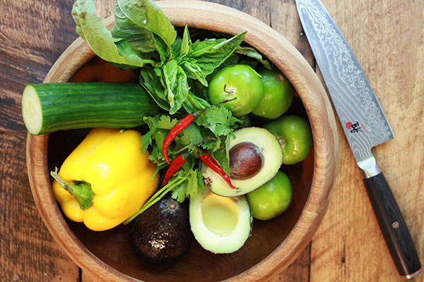 fresh veggies for making gazpacho soup in wooden bowl and chef's knife on the side