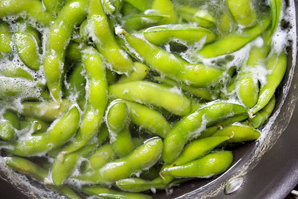 Edamame pods boiling in a pot of water.