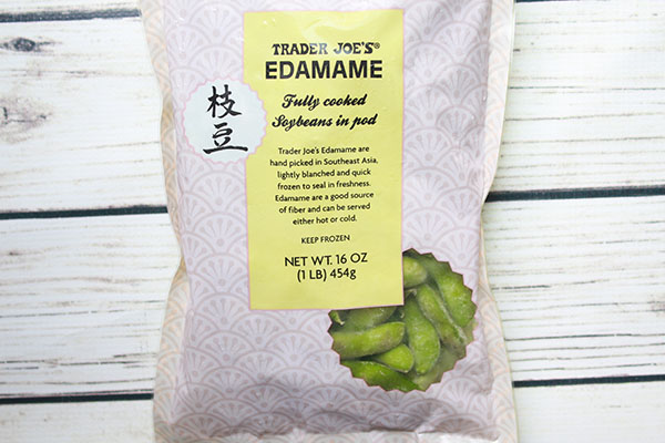 A 16-ounce bag of Trader Joe's frozen edamame on a white plank board.