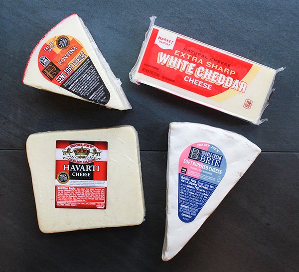 Four different blocks of cheese placed in top of a black surface.