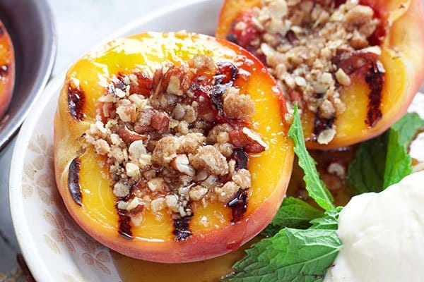 grilled peaches halved and topped with a five spice oats crumble and a scoop of vanilla ice cream