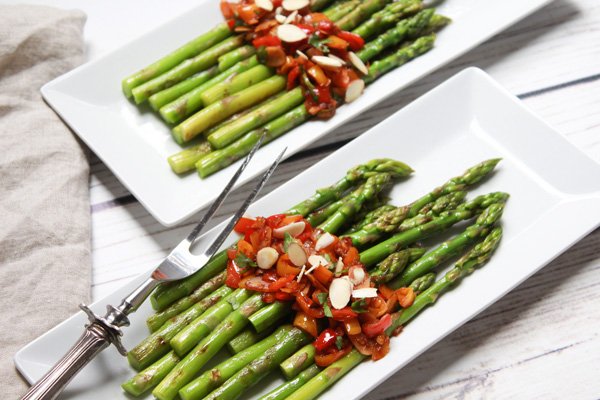 Asian Grilled Sweet and Spicy Asparagus Beautiful grilled asparagus spears with an Asian sweet and spicy pepper sauce placed on top of two narrow white plates with an asparagus spear on top.