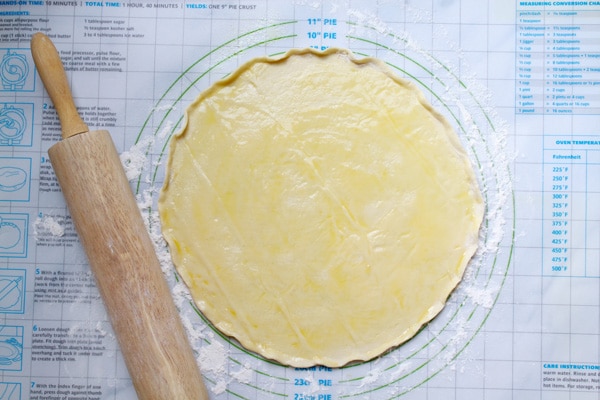 pizza dough Rolled out pizza dough in a round shape on top of a floured pastry rolling surface with a rolling pin on the side.