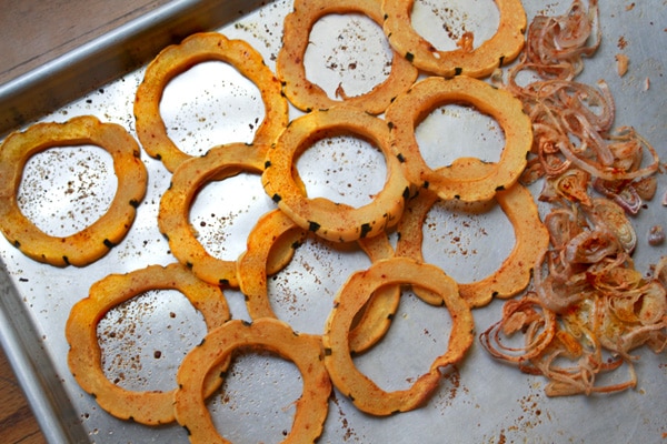 roasted delicata squash Rings of roasted delicata squash on top of a baking sheet with roasted shallots on the side.