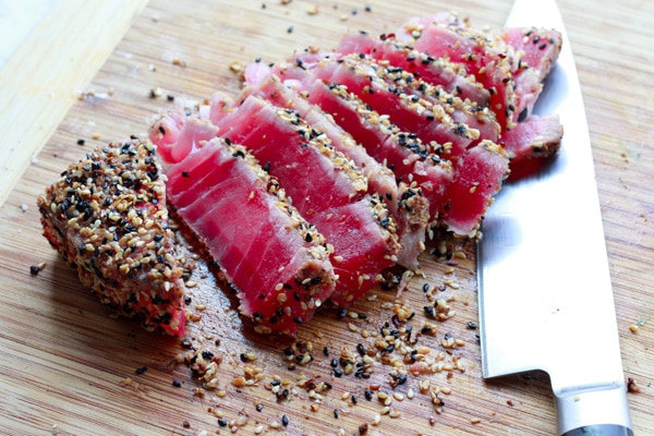 sesame seared tuna Slices of sesame seared tuna on a wooden cutting board with a chef's knife on the side.