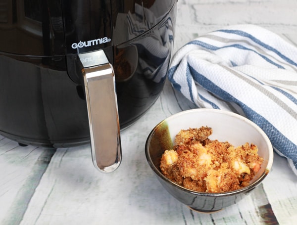 bang bang shrimp tacos in a bowl along side an air fryer.