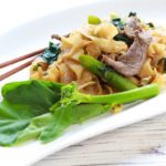 Thai Pad See Ew stir fried noodles on a plate with chopsticks and Chinese broccoli