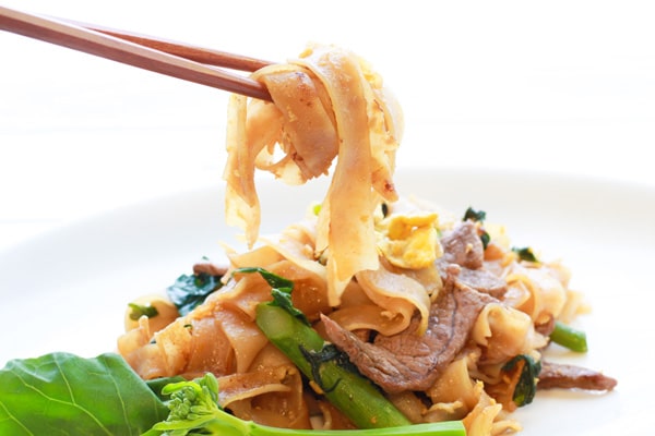 Pad See Ew (stir fried noodles) Thai Pad See Ew stir fried noodles on a plate with chopsticks and Chinese broccoli.