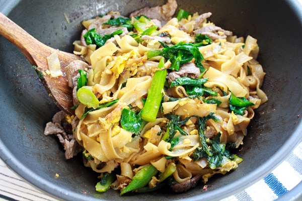 Pad See Ew (stir fried noodles) Thai Pad See Ew stir fried noodles with broccoli in a wok with a wooden spatula.