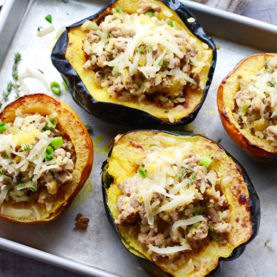 stuffed roasted acorn squash with ground turkey and rice on a baking tray.