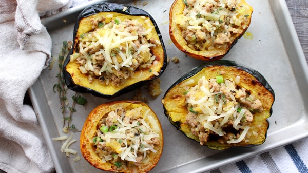 stuffed acorn squash stuffed roasted acorn squash with ground turkey and rice on a baking tray.