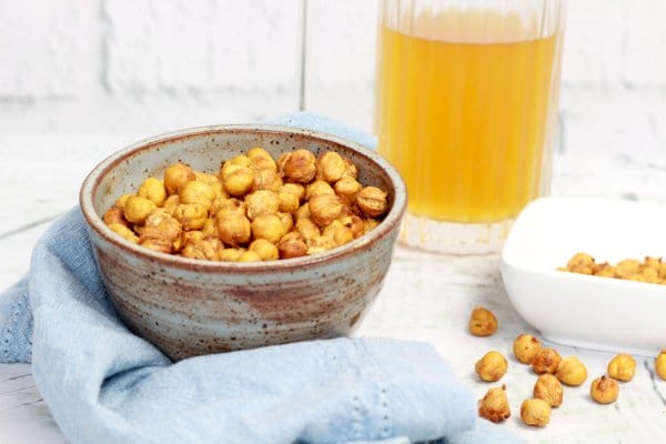 crispy spicy chickpeas in a gray bowl with a glass of frosty cold beer in the background.