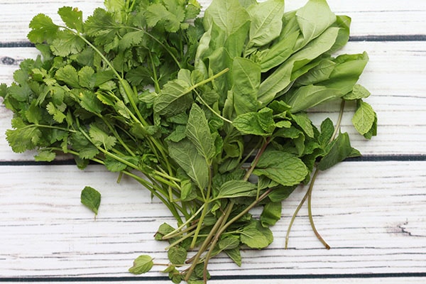 Fresh green herbs on a white wooden board.