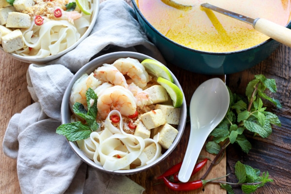 Singapore laksa with shrimp and tofu Singapore laksa with shrimp, tofu, and rice noodles in a bowl and in a Dutch oven with ladle.