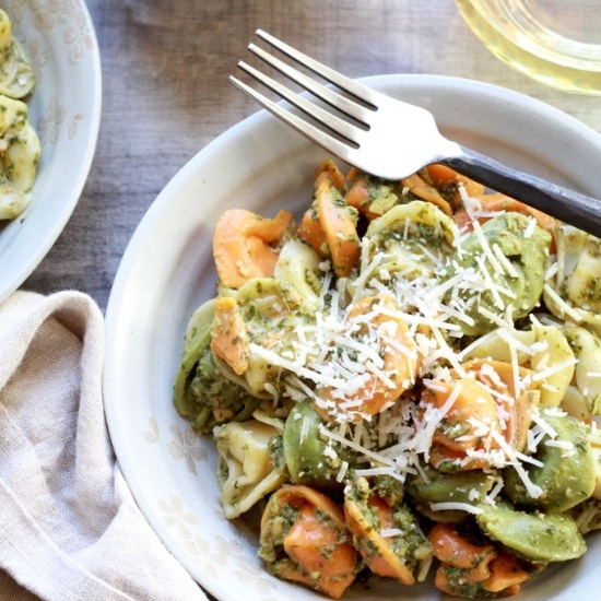 Tri-color tortellini in a white bowl tossed with Thai pesto sauce