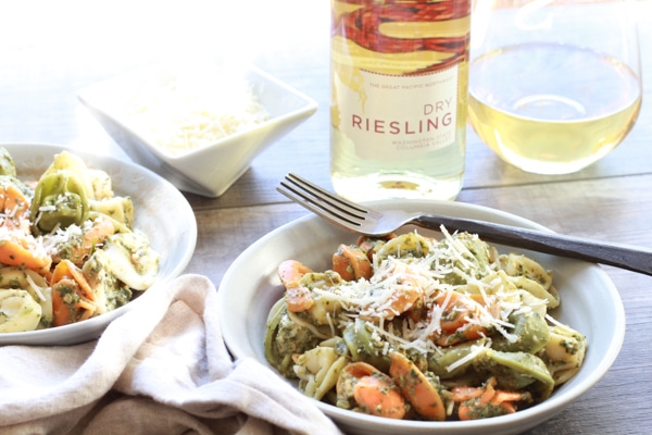 tri-color tortellini with white wine Tri-color tortellini in two white bowls tossed in a Thai pesto sauce with a fork on the side of the bowl and a glass and bottle of Reisling wine in the background.