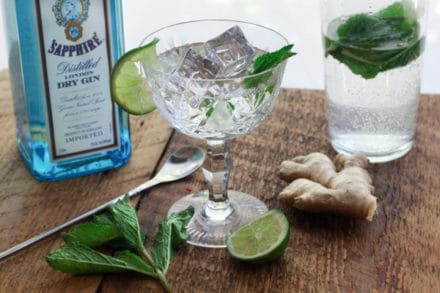 minty gin fizz cocktail in a crystal glass with a lime slice and bottle of Sapphire gin