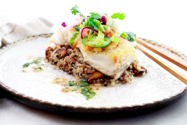 pan seared halibut on top of a bed of quinoa and topped with a spicy nuoc cham slaw