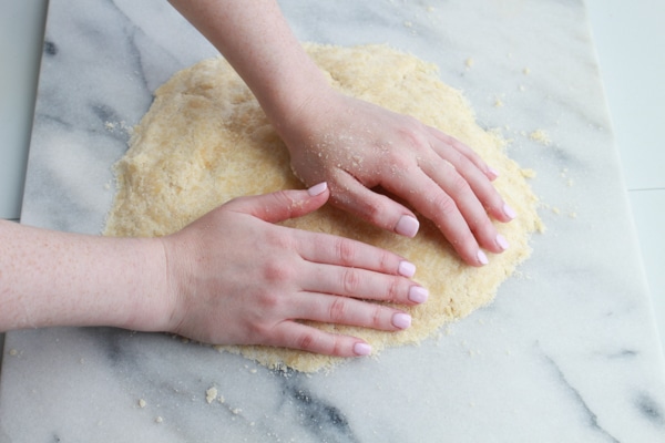 Chinese almond cookies A woman's hands kneading Chinese almond cookie dough on a pastry board on top of a marble suirface.