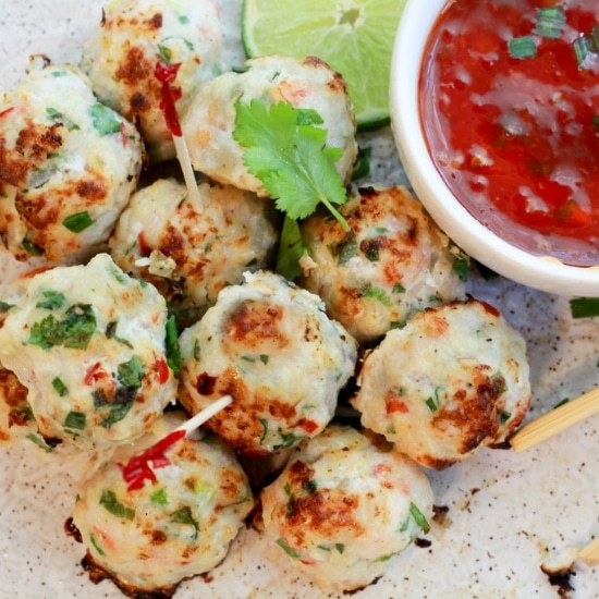 spicy baked shrimp balls piled hight with party toothpicks and a side of sweet chili sauce
