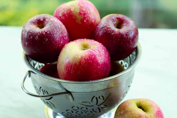 a bowl of red apples in a stainless steel bowl