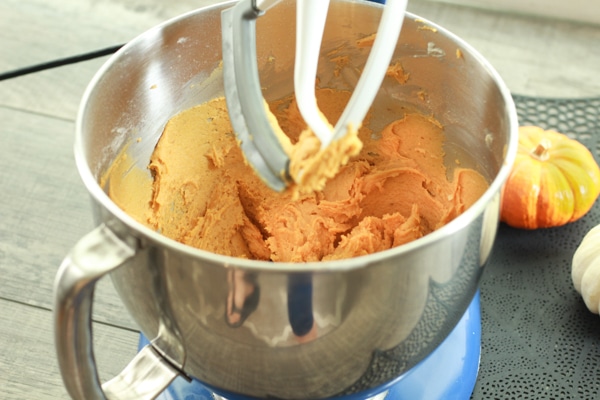 pumpkin cookie batter in a silver mixing bowl with baby pumpkins on the side