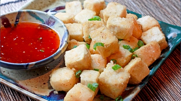 crispy tofu cubes on a square serving plate with a side of sweet chili dipping sauce