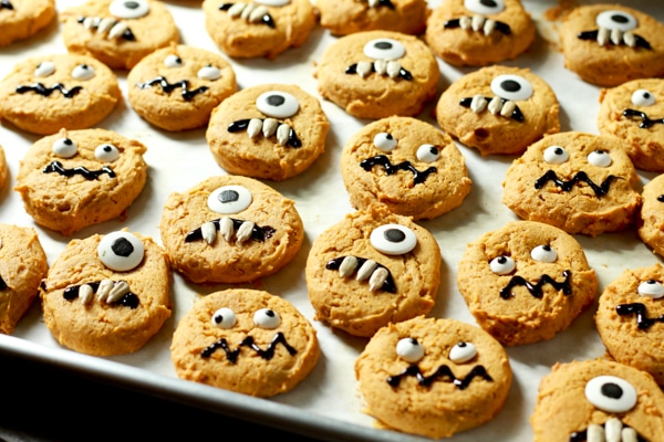 decorated pumpkin monster cookies on a baking sheet lined with parchment paper