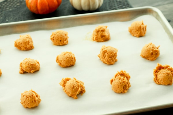 raw pumpkin cookie dough rounds on a baking sheet lined with parchment paper ready for the oven