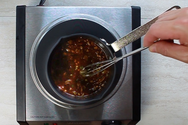 marinade for pork tenderloin in a small sauce pot with man stirring with a whisk