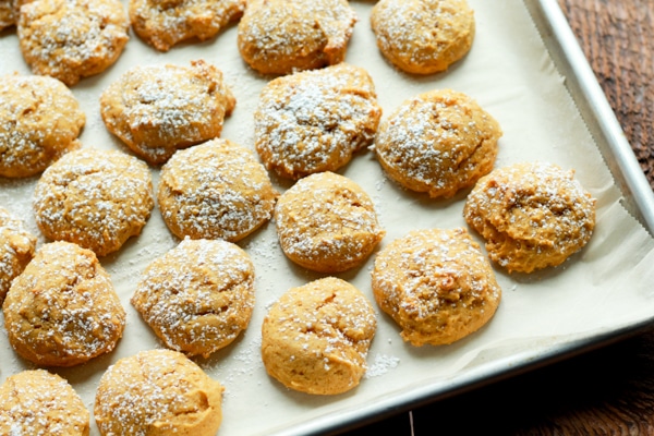 baked pumpkin spice cookies sprinkled with powdered sugar on a parchment-lined baking tray