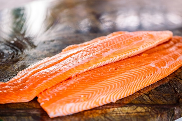 raw salmon filets on top of a wooden board