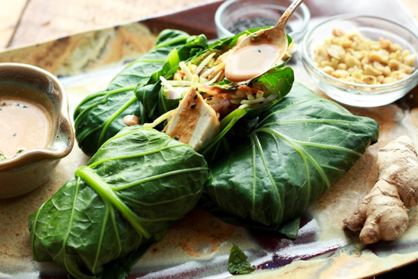 tofu collard wraps on a platter with a peanut sauce on the side