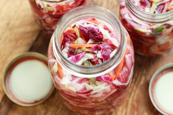 pickled veggies in three canning jars on a wooden board